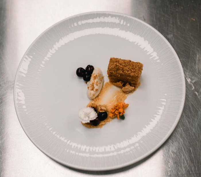 Plated dessert with blueberries, ice cream and edible flowers